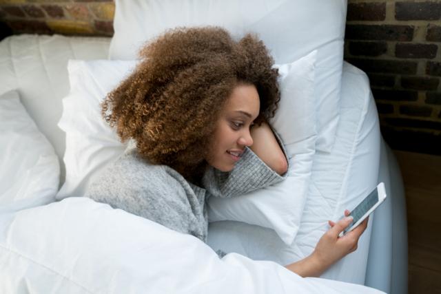 person in bed checking phone
