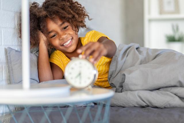 child in bed looking at clock