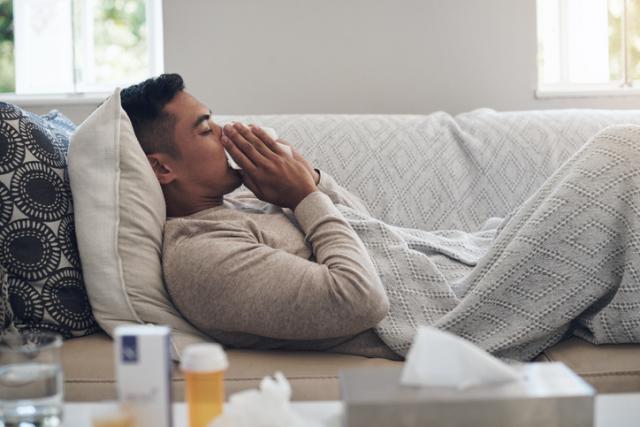 man on couch wiping nose