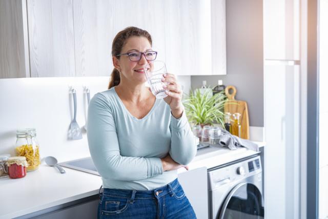 woman in kitchen drinking water