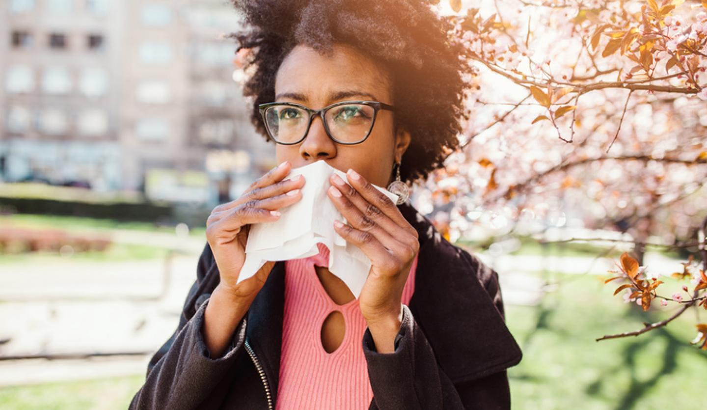 woman outside holding tissue to mouth