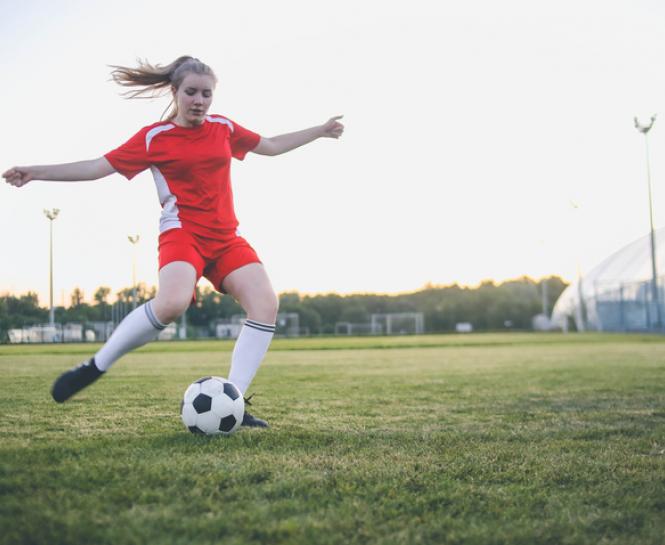 young woman playing soccer on field