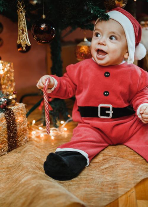 baby in santa suit under christmas tree