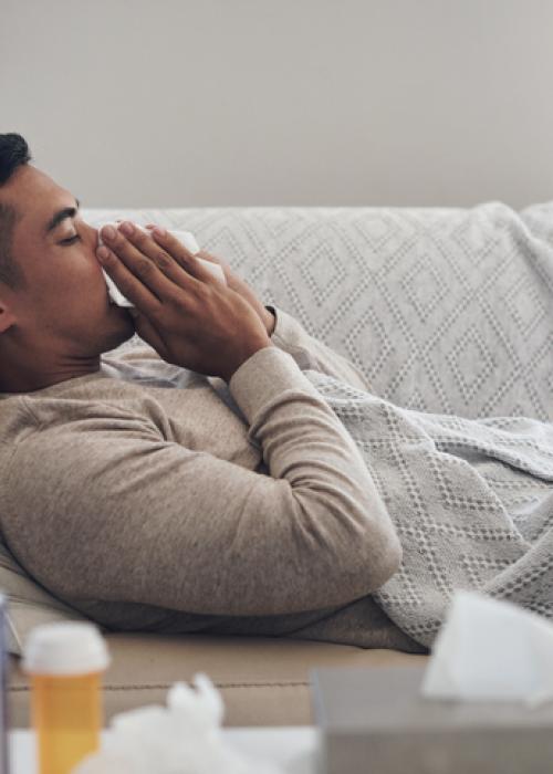 man on couch wiping nose